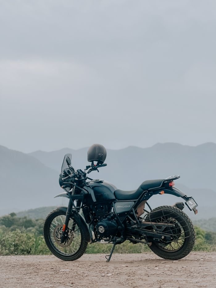 Home A rugged adventure motorcycle parked on a dirt road with a scenic view of mountains under a cloudy sky.